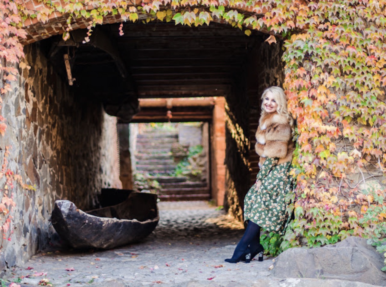 Artist Marina Stognieva in a dark castle passage beside an old boat